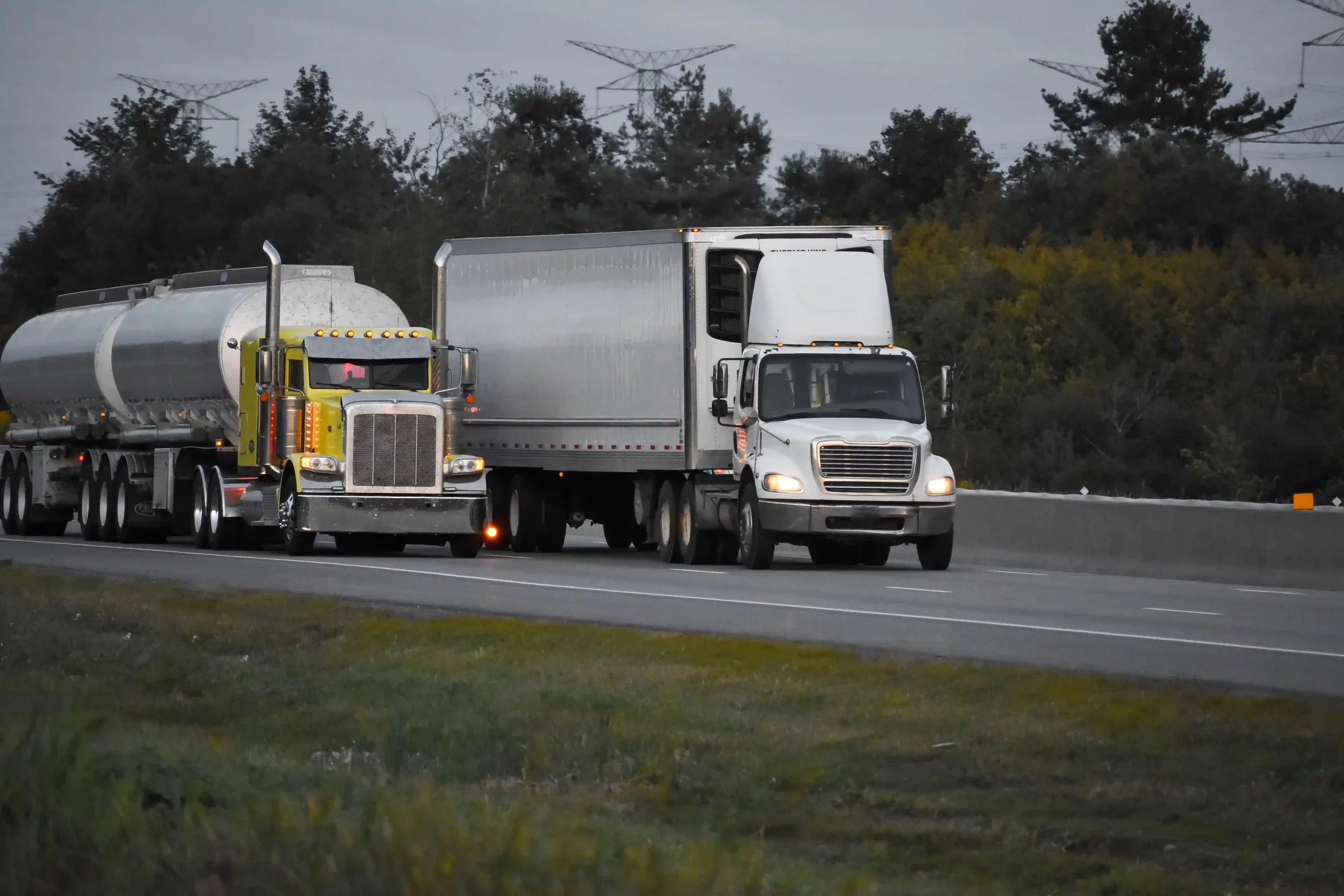 1-trailer-trucks-driving-road-surrounded-by-beautiful-green-trees
